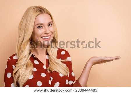 Portrait of charming young woman promoter demonstrate hand product proposition sale object empty space isolated on beige color background