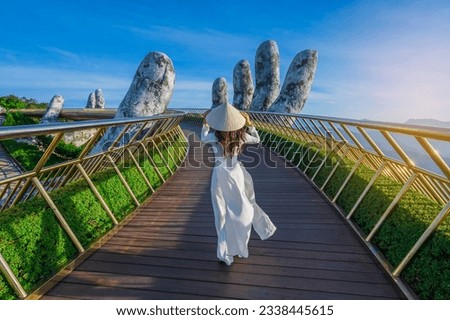 Vietnamese girl with traditional dress (ao dai) on Golden bridge at the top of the Ba Na Hills, Vietnam Royalty-Free Stock Photo #2338445615