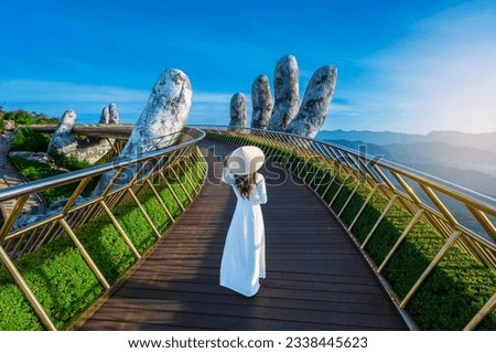 Vietnamese girl with traditional dress (ao dai) on Golden bridge at the top of the Ba Na Hills, Vietnam Royalty-Free Stock Photo #2338445623