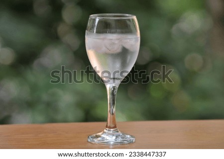 Mineral water in a wineglass with ice, with fogged glass due to high outside temperature Royalty-Free Stock Photo #2338447337