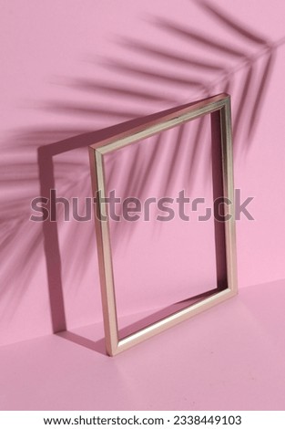 Golden frame on a pink background with palm leaf shadow. Creative layout, minimalism