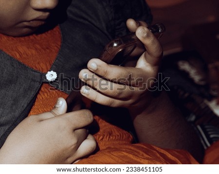 Cell phone games playing  by Indian ethnic girl child- low light edit - selective focus
