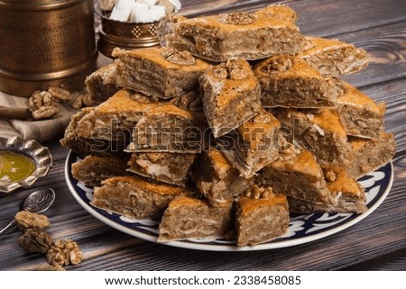 Traditional arabic dessert baklava with walnuts and honey on a wooden concrete table. Delicious rhombus shaped Turkish baklava. Traditional eastern dessert.
