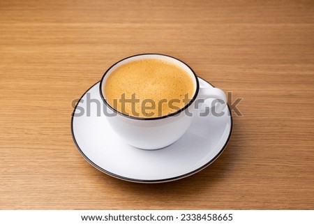 cappuccino in a white cup on a wooden table. fresh morning coffee in the restaurant Royalty-Free Stock Photo #2338458665