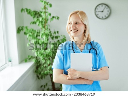 Portrait of a young female nurse holding tablet in her office or clinic