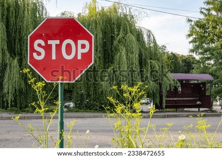 STOP sign close-up, the sign is overgrown with bushes, in the background there is a road, trees