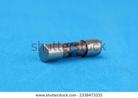 The TV's power fuse has blown due to a power surge. The glass fuse burned out and became opaque. Royalty-Free Stock Photo #2338473335