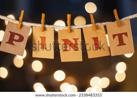 The words PIN IT printed on clothespin clipped cards in front of defocused glowing lights.