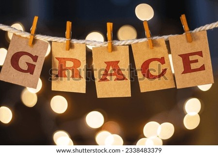 The word GRACE printed on clothespin clipped cards in front of defocused glowing lights. Royalty-Free Stock Photo #2338483379