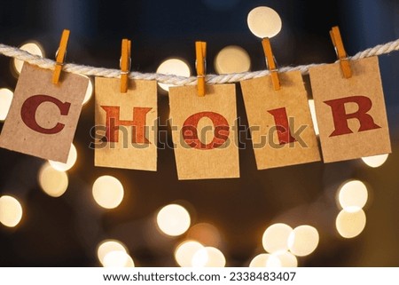 The word CHOIR printed on clothespin clipped cards in front of defocused glowing lights.