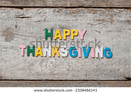 The colorful words -HAPPY THANKSGIVING- made with wooden letters on old wooden board.
