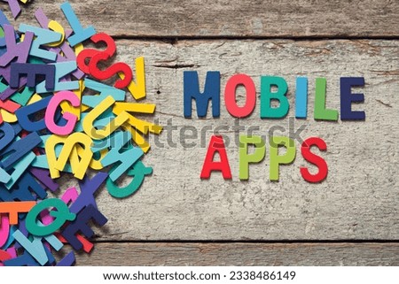 The colorful words -MOBILE APPS- made with wooden letters next to a pile of other letters over old wooden board.