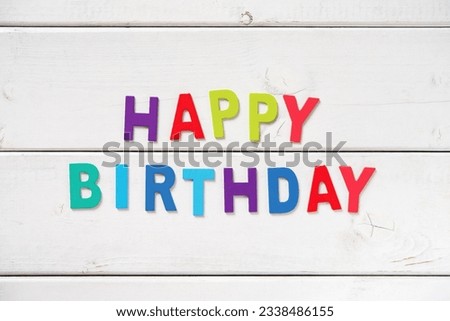 The colorful words -HAPPY BIRTHDAY- made with wooden letters on white board.