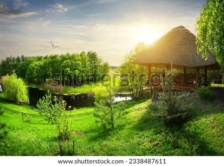 Wooden arbour with thatched roof near river