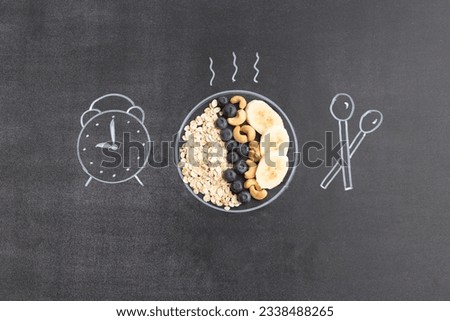Oat flakes with nuts and fruits. Breakfast concept. The plate, spoon and clock are drawn with chalk on a black board.