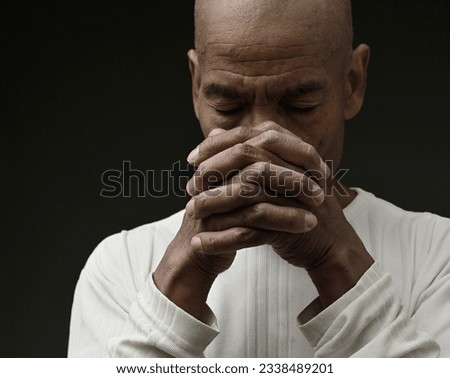 man praying to god with hands together Caribbean man praying with people stock image stock photo	
