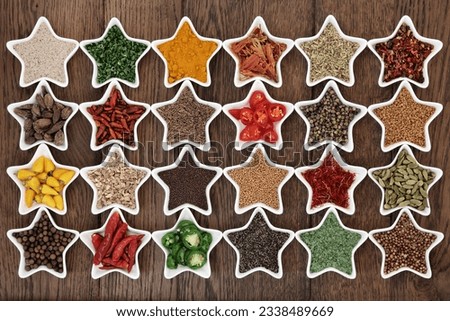 Large herb and spice selection in star shaped porcelain dishes over old oak background.