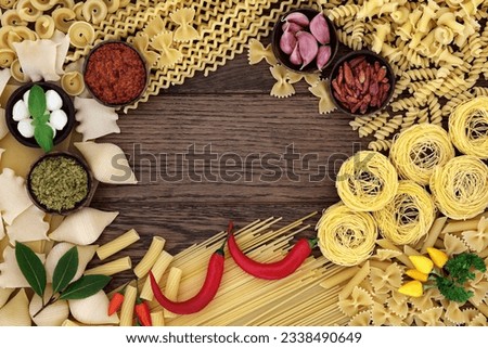 Spaghetti pasta selection and italian food ingredients forming an abstract background border over old oak wood.