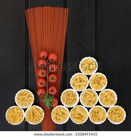 Tomato spaghetti and italian pasta dried food selection in porcelain crinkle bowls over dark wood background.