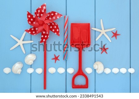 Toy windmill, spade, rock candy and sea shells over wooden blue background.