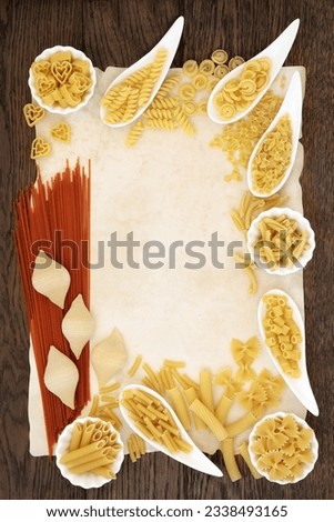 Pasta selection and tomato spaghetti food abstract forming a border over old parchment and oak bakground.