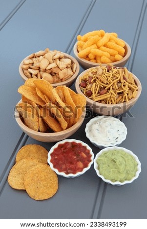 Savoury snack and dip party food selection in wooden bowls and porcelain dishes.