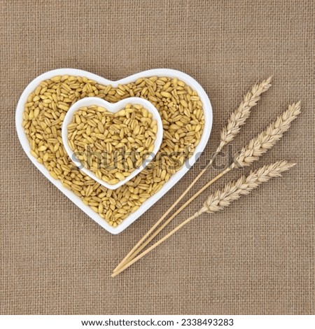 Kamut khorasan wheat in heart shaped dishes over hessian background with ears of wheat.