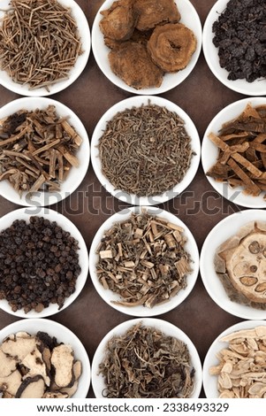 Chinese herbal medicine selection in porcelain bowls over brown paper background.