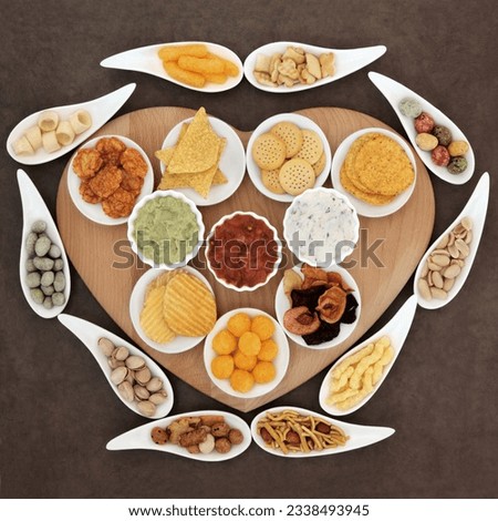 Savoury snack and dip party food selection in porcelain dishes on a heart shaped wooden board.