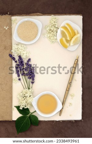 Elderflower and lavender champagne ingredients with old pen over natural hemp notebook and lokta paper background.