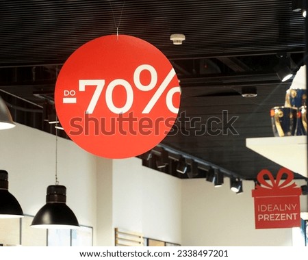the sign in the mall is round red with the information about the summary at 70 percent. sale. salons. the shops