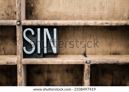 The word -SIN- written in vintage metal letterpress type in a wooden drawer with dividers.