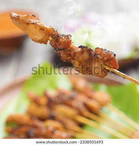 Tasty chicken sate or satay, skewered and grilled meat, served with peanut sauce. Fresh cooked with steamed and smoke. Hot and spicy Asian dish.