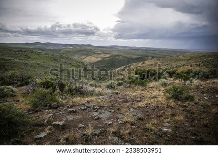 High desert terrain of rolling green mountain sides near Twin Falls Idaho in summer with stormy skies Royalty-Free Stock Photo #2338503951