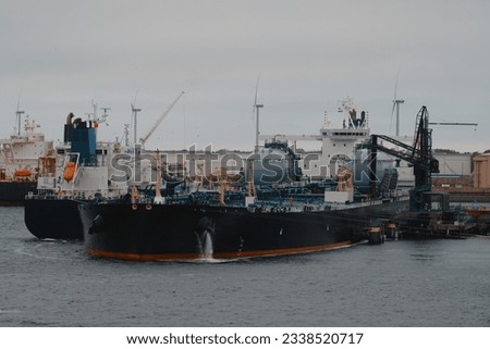 Floating storage and regasification unit. Liquified natural gas bunkering vessel and oil tanker powered by LNG in the port during the ship-to-ship operations. Royalty-Free Stock Photo #2338520717