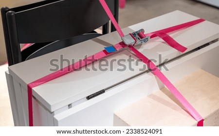 Pink ratchet straps securing desk and chair. Furniture moving. Cargo equipment. Royalty-Free Stock Photo #2338524091