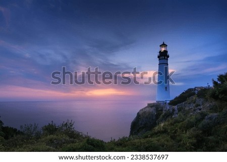 Coastal Security: Illuminated Lighthouse Guides Travelers to Protected Beach at Sunset Royalty-Free Stock Photo #2338537697