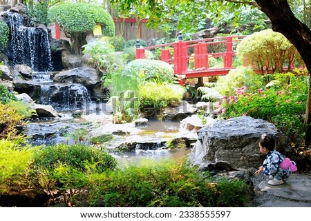 Japanese garden style with red bridge and child sitting in Chiangmai Thailand.