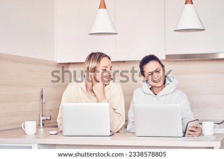 Two women talk and smile, discuss an online presentation, work on a joint project, share ideas during teamwork. High quality photo
