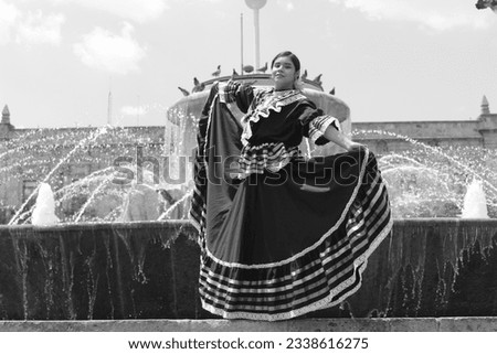 Young woman wearing her beautiful typical Guadalajara costume on the edge of a fountain