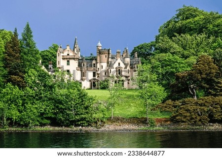 Scottish castle by a lakeshore in the forest Royalty-Free Stock Photo #2338644877