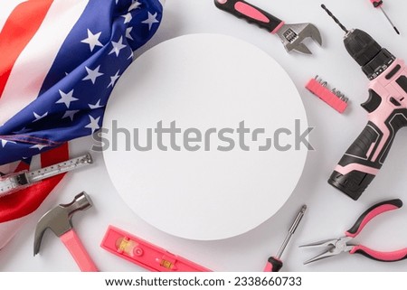 Recognizing contributions of women in labor on American Labor Day. Top view picture showcasing American flag and construction tools on white isolated backdrop, allowing for advert or text placement
