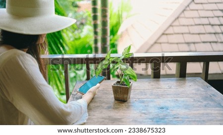 vacation concept Woman hand holding black smartphone relax at hotel resort enjoying luxury lifestyle outdoor