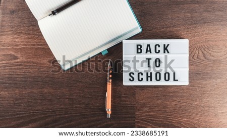 Back to school concept. School supplies on wooden background. Back to school lettering on white letter board. Copy space for text. Selective focus included.