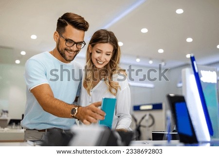Shopping a new digital device. Happy couple buying a smartphone in store. Royalty-Free Stock Photo #2338692803