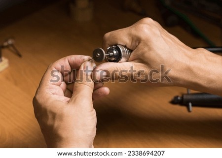 Close-up of Caucasian male hands of a jeweler making repairs to a silver bracelet. Craft, craftsman works with silver. Royalty-Free Stock Photo #2338694207
