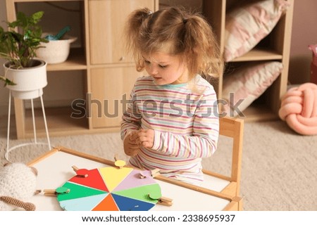 Cute little girl playing matching game with clothespins at home Royalty-Free Stock Photo #2338695937