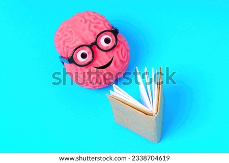 Smiling brain character donning nerdy glasses, happily engrossed in reading a book, isolated on blue background.