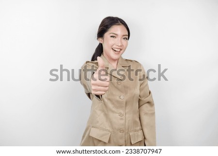 A young Asian woman in brown khaki uniform showing thumbs up or OK sign with her fingers. Indonesian government worker.