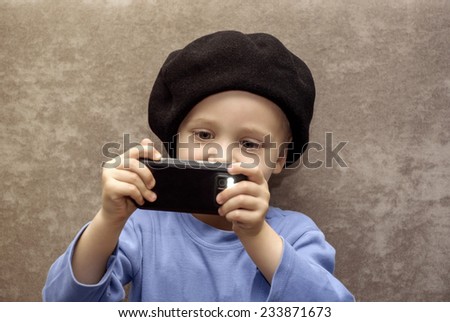 Little boy in hat taking pictures with your smartphone.